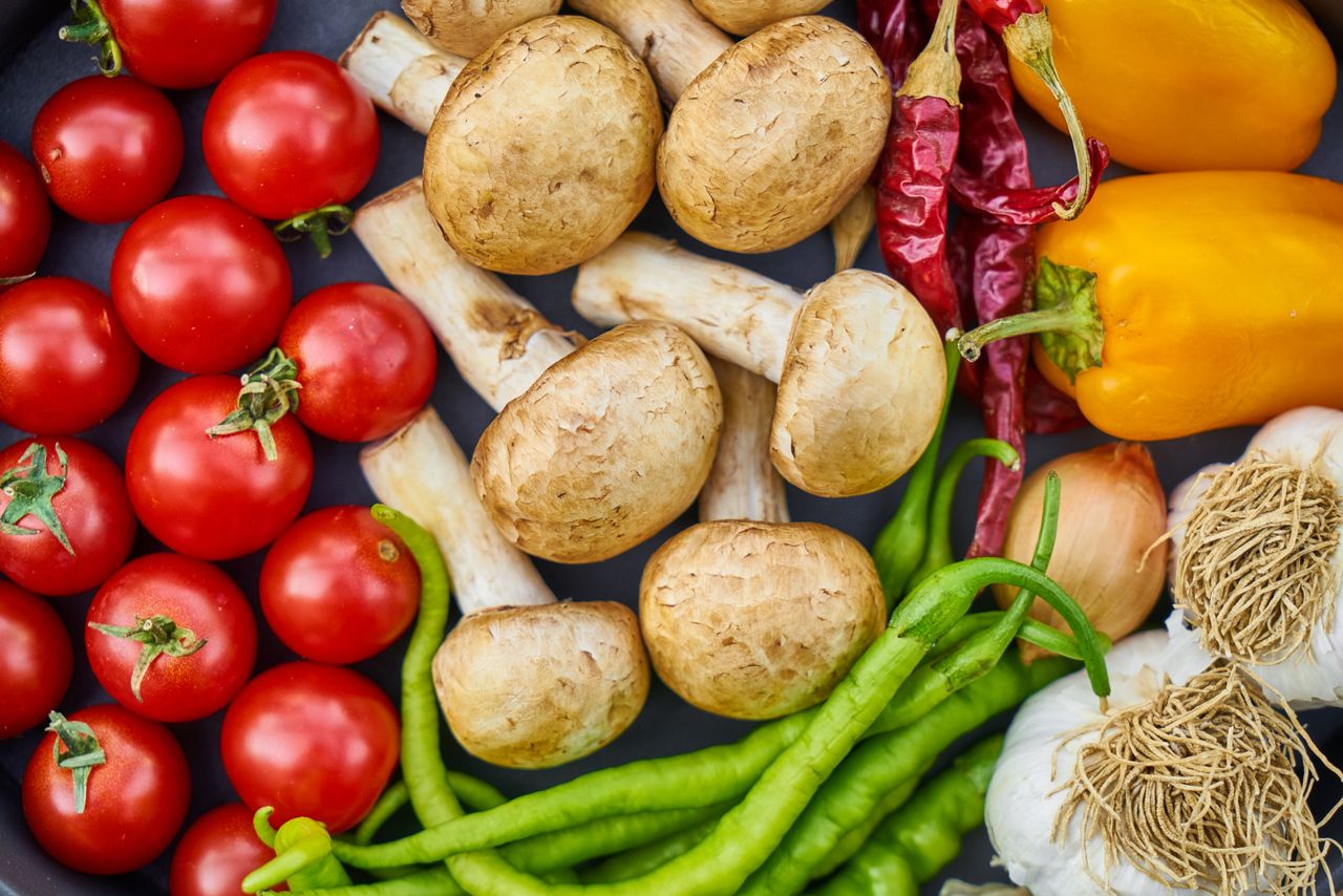 Home A vibrant assortment of fresh vegetables and mushrooms arranged in a flat lay.