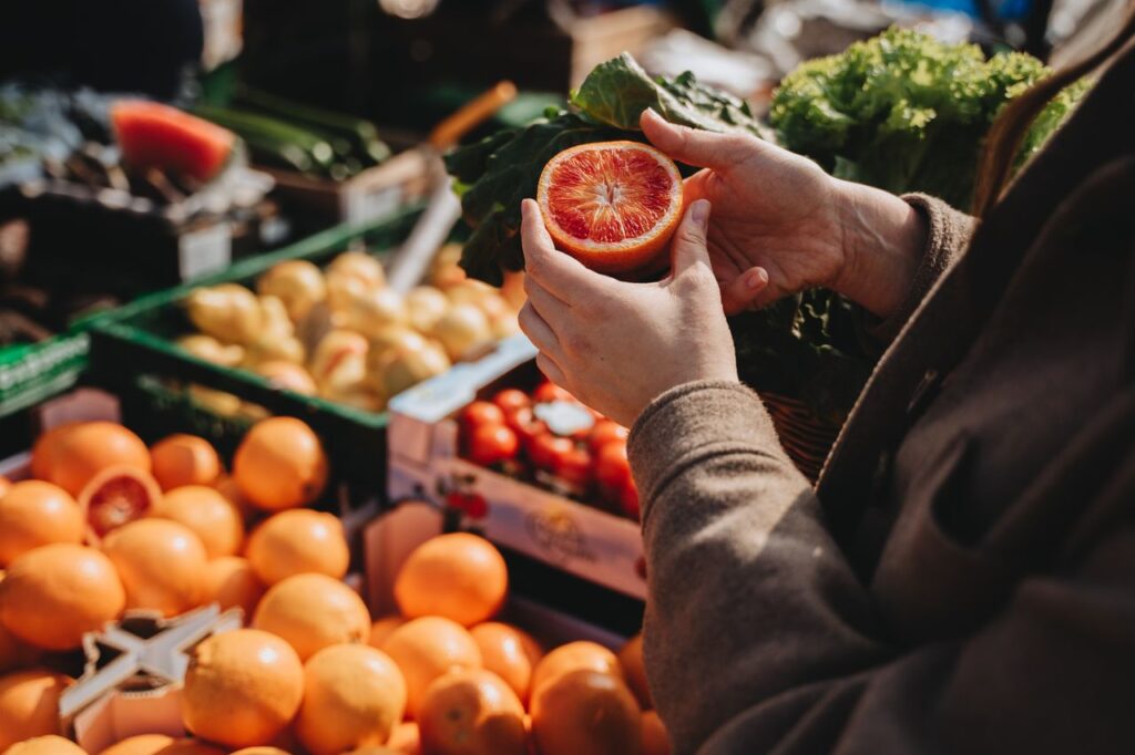 The Art of Drawing Readers In: Your attractive post title goes here A close-up of a person holding a sliced orange at an outdoor market, showcasing fresh produce.