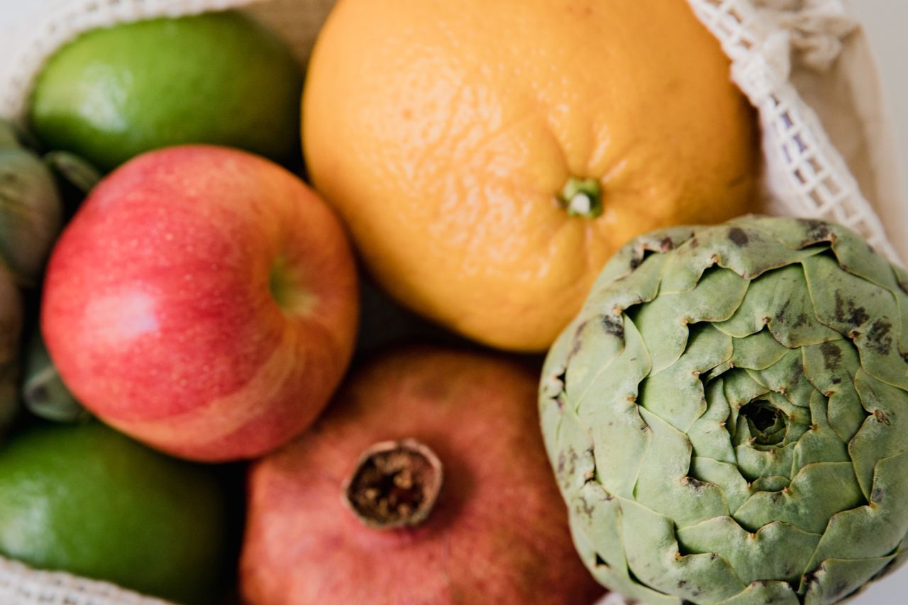 Home A colorful assortment of fresh fruits and vegetables in a mesh bag, promoting healthy eating.
